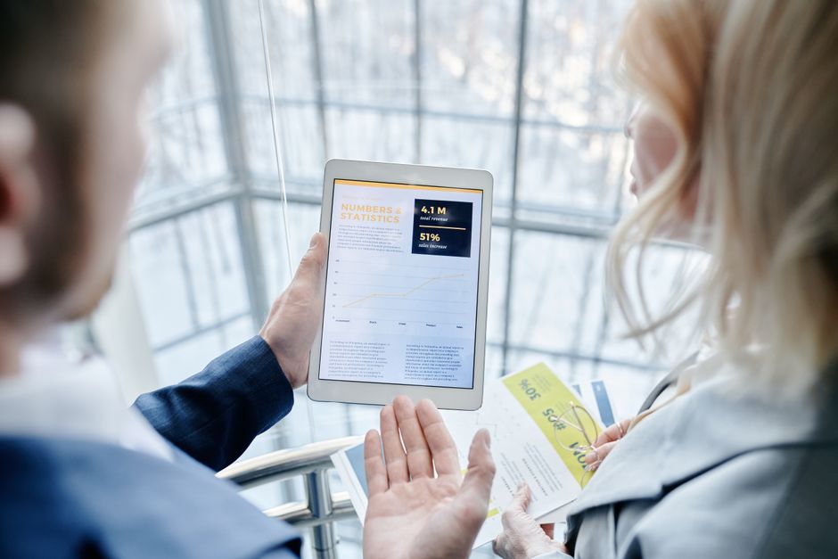 marketing digital Maroc — Des professionnels discutent d'analytique sur une tablette dans un bureau moderne.